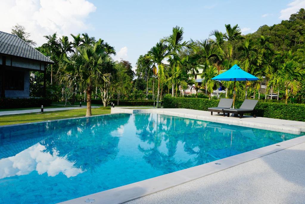 a swimming pool with a bench and an umbrella at Na Vela Village - Adults Only Hotel in Ko Lanta