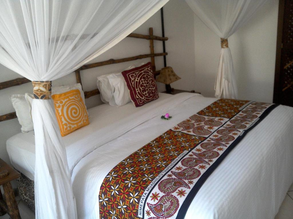 1 dormitorio con 1 cama grande y cortinas blancas en Kahama Hotel Mombasa, en Bamburi