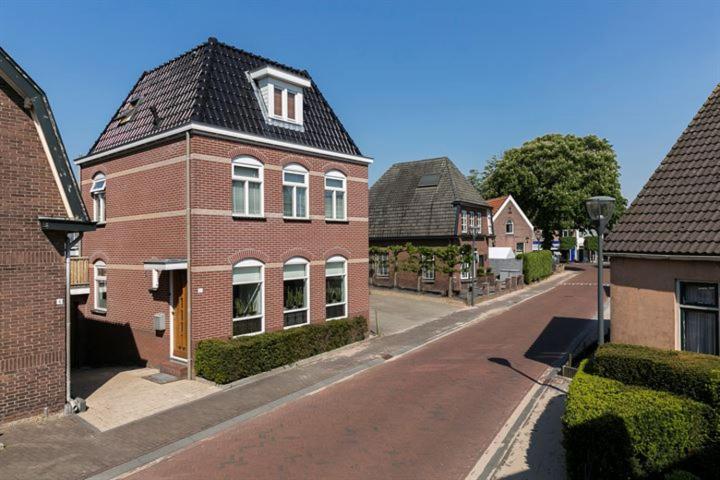 a brick house with a black roof on a street at B&B Freydag in Rheden