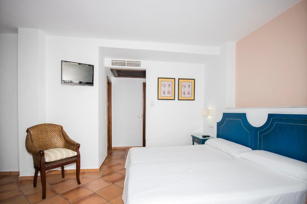 a bedroom with a bed and a chair and a tv at Hostal Doña Lola Marina in Zahara de los Atunes