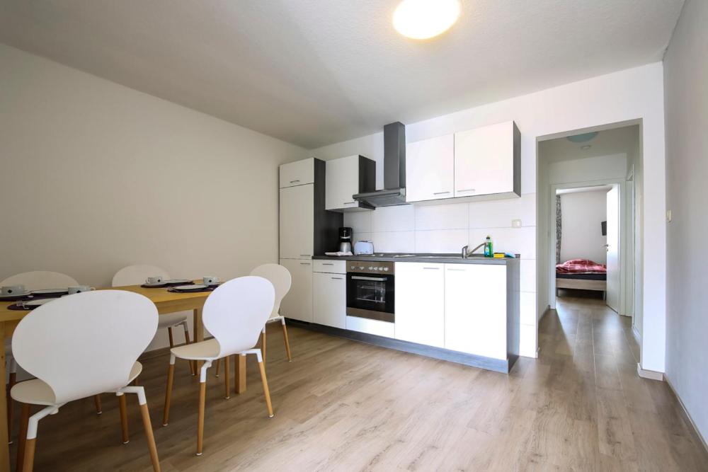 a kitchen with white cabinets and white chairs in a room at Monteurwohnung 2 Zimmer in Havekost