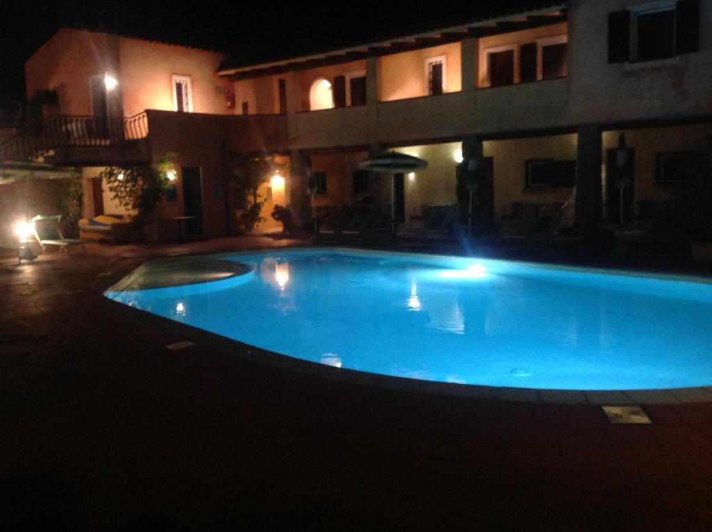 a large blue swimming pool in front of a building at night at Hotel Villa Gemella in Baja Sardinia