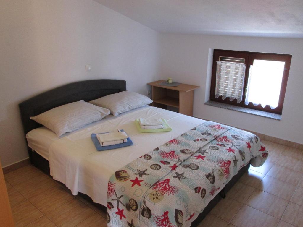 a bedroom with a large bed with a blanket and a window at Apartment Krizanovic in Malinska