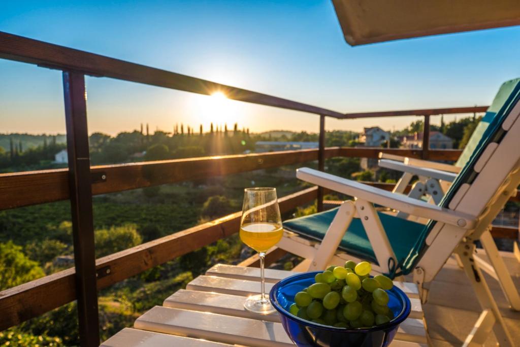 une table avec un verre de vin et un bol de raisin dans l'établissement Le Petit, à Čilipi