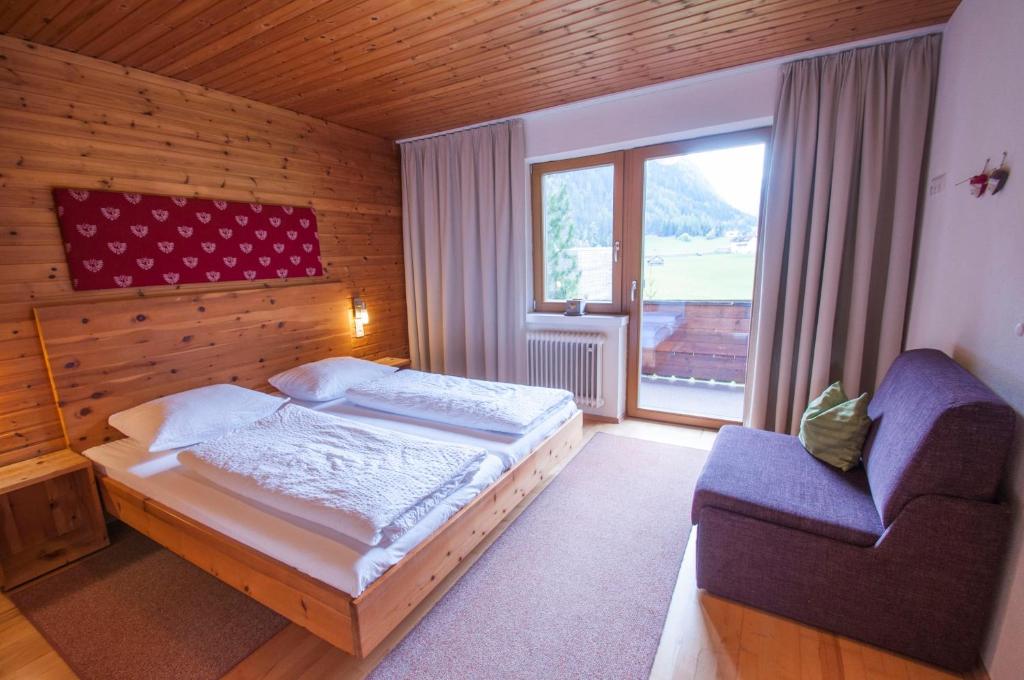 ein Schlafzimmer mit einem Bett, einem Stuhl und einem Fenster in der Unterkunft Haus Kaunergrat in Kaunertal