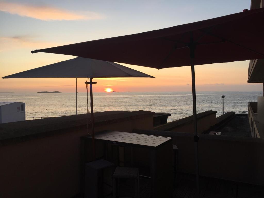 2 sombrillas y una mesa en un balcón con vistas al océano en La Caravelle au plus près de la mer en Saint-Malo