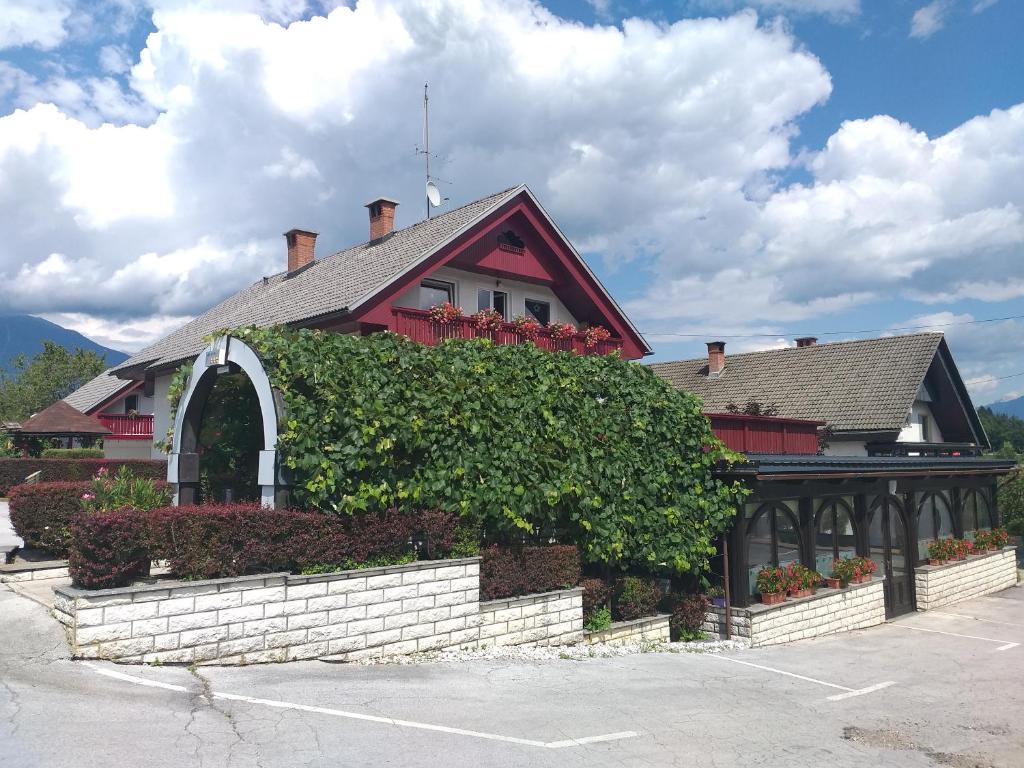 une maison rouge avec un grand bush devant elle dans l'établissement APARTMENTS 1A RIBNO - BLED, à Bled