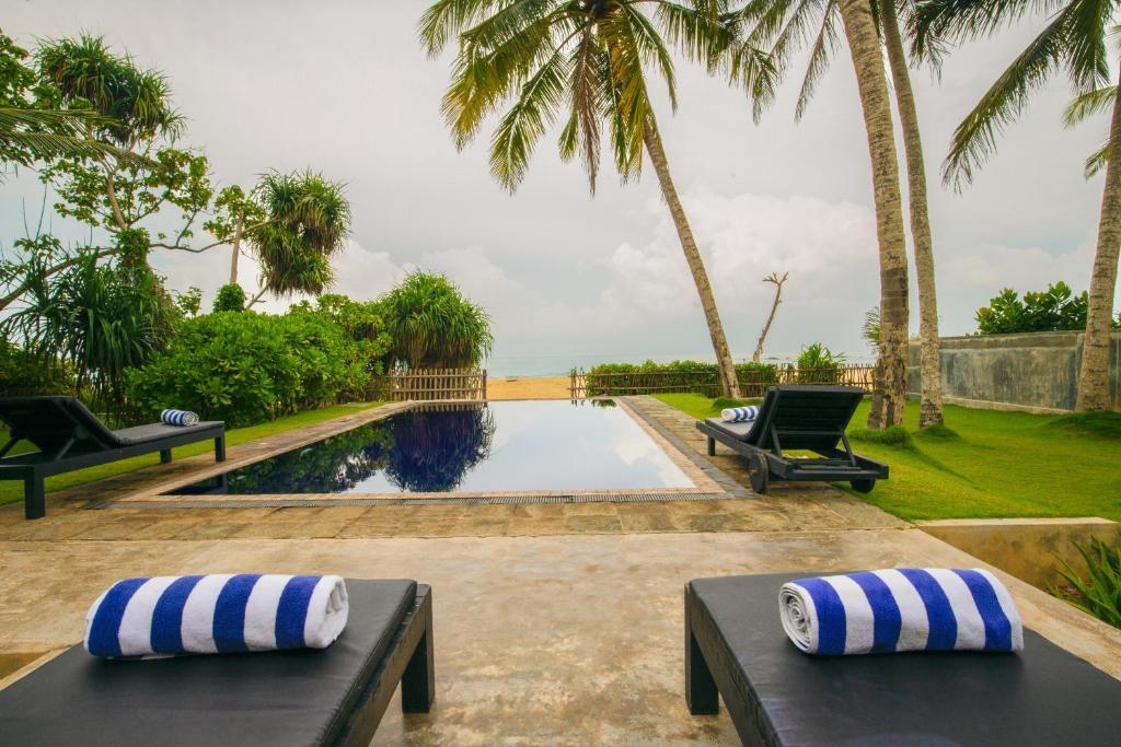 - une piscine avec 2 bancs et des palmiers dans l'établissement Villananda, à Ambalangoda