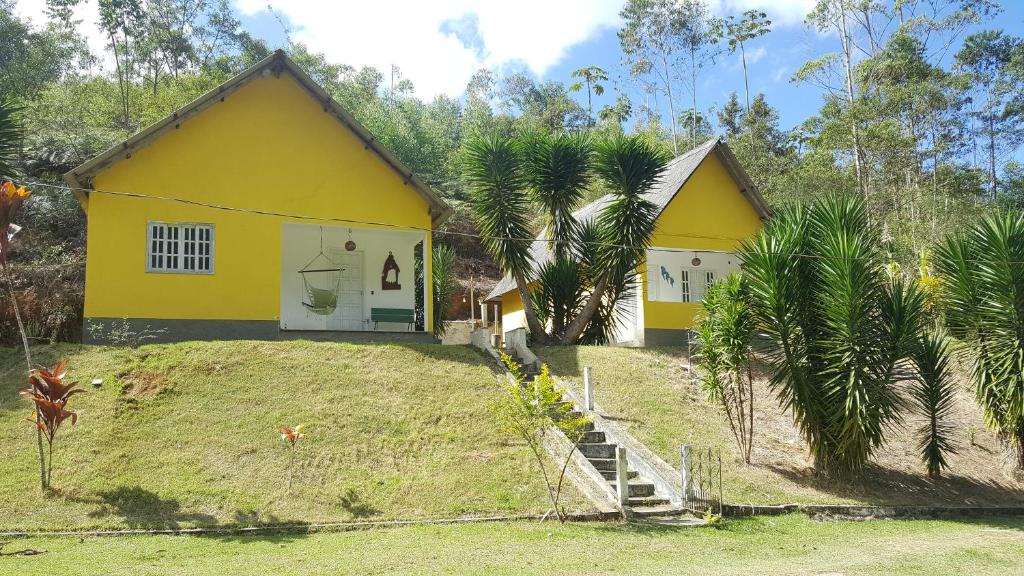 ein gelbes Haus auf einem Hügel mit Palmen in der Unterkunft Belo Canto Chalés in Santa Teresa