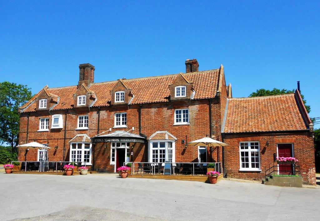 Kings Head Hotel في North Elmham: مبنى من الطوب الأحمر كبير مع نوافذ بيضاء