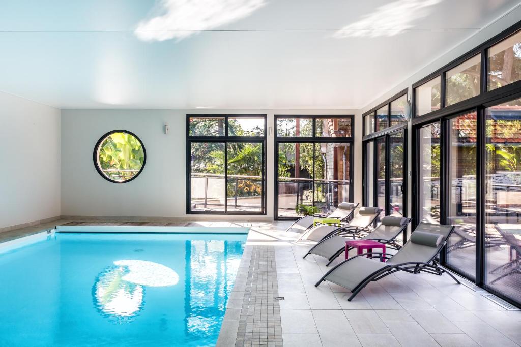an indoor swimming pool with chairs and tables in a house at Résid'Spa Loire & Sèvre in Rezé