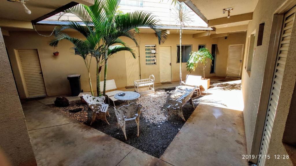eine Terrasse mit einer Palme, einem Tisch und Stühlen in der Unterkunft Flat Três Marias in Goiânia