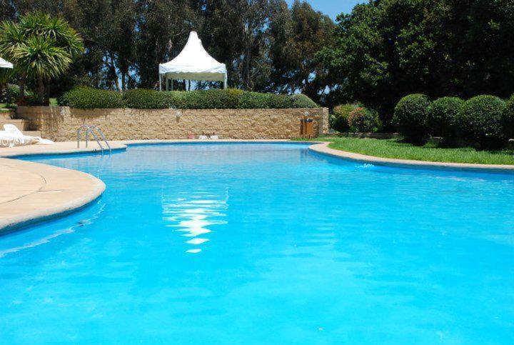 una gran piscina azul con una tienda blanca en el fondo en Departamentos Mednav Mantagua en Concón