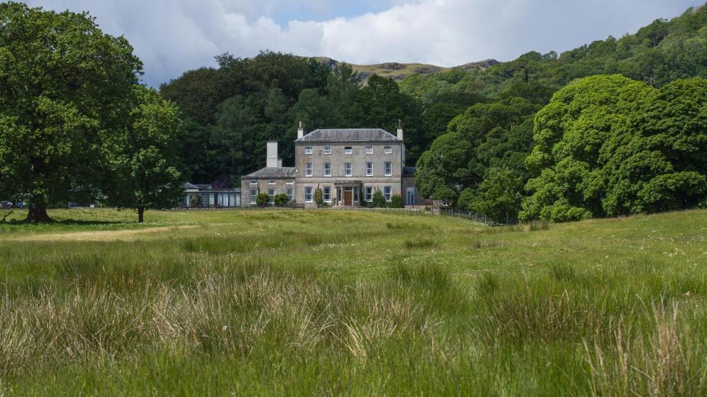 una casa grande en una colina en un campo en Brathay Hall - Brathay Trust, en Ambleside