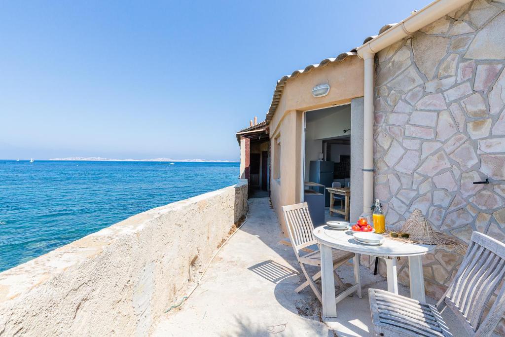 - une table et des chaises sur une terrasse à côté de l'eau dans l'établissement Le Grand Bleu- Superbe Maison avec Terrasse vue sur Mer, à Marseille