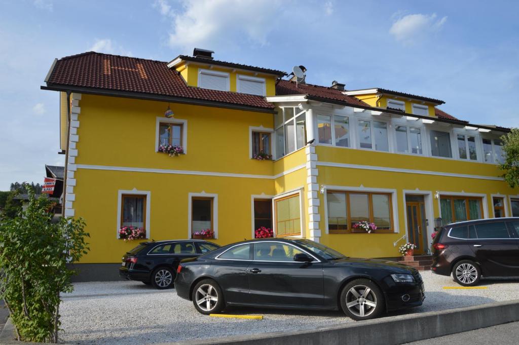 un coche negro estacionado frente a un edificio amarillo en Pension Hrnjic, en Seeboden
