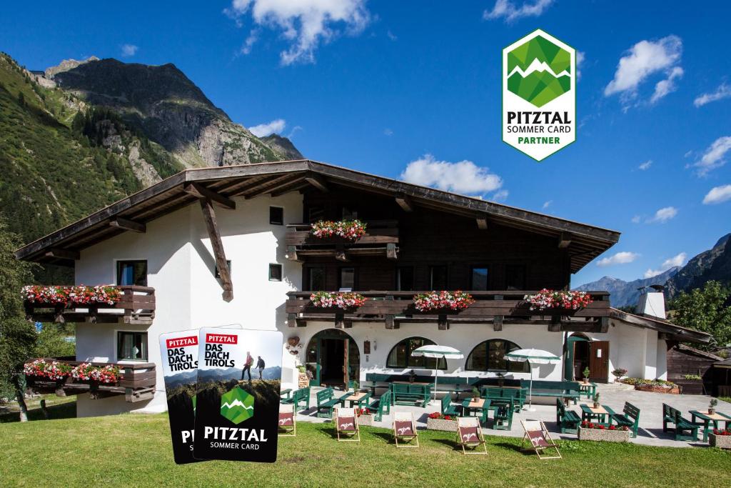 a building with chairs in front of it at Natur Residenz Anger Alm - Adults only in Sankt Leonhard im Pitztal
