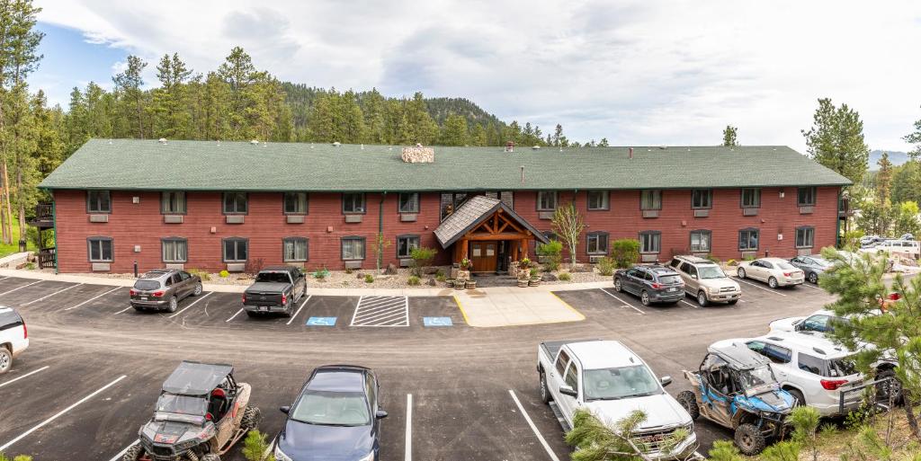 ein großes rotes Backsteingebäude mit Autos auf einem Parkplatz in der Unterkunft Lodge at Palmer Gulch in Hill City