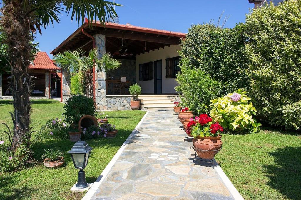 Giorgio Home - Amazing House 3BD - 400m by the sea في باراليا سكوتنيس: حديقة بها نباتات الفخار أمام المنزل