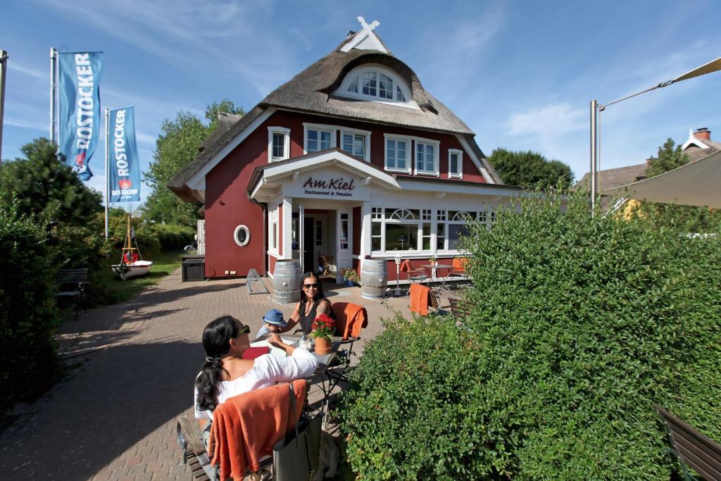 a group of people sitting in front of a building at Haus am Kiel in Ahrenshoop