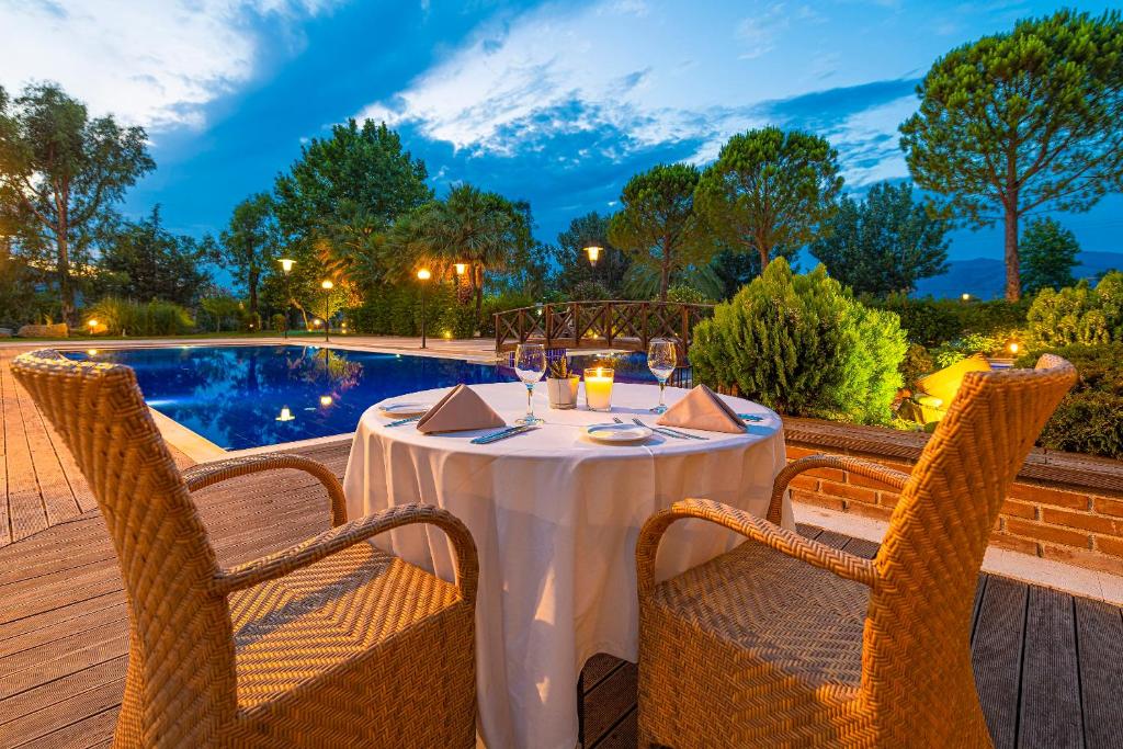 a table with wine glasses on a deck next to a pool at Hotel Byzantino in Arta