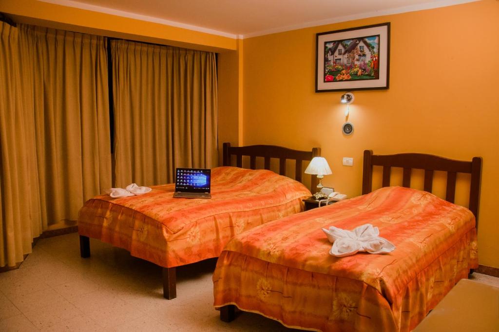a hotel room with two beds with a laptop on it at Hotel Amoretto in Trujillo