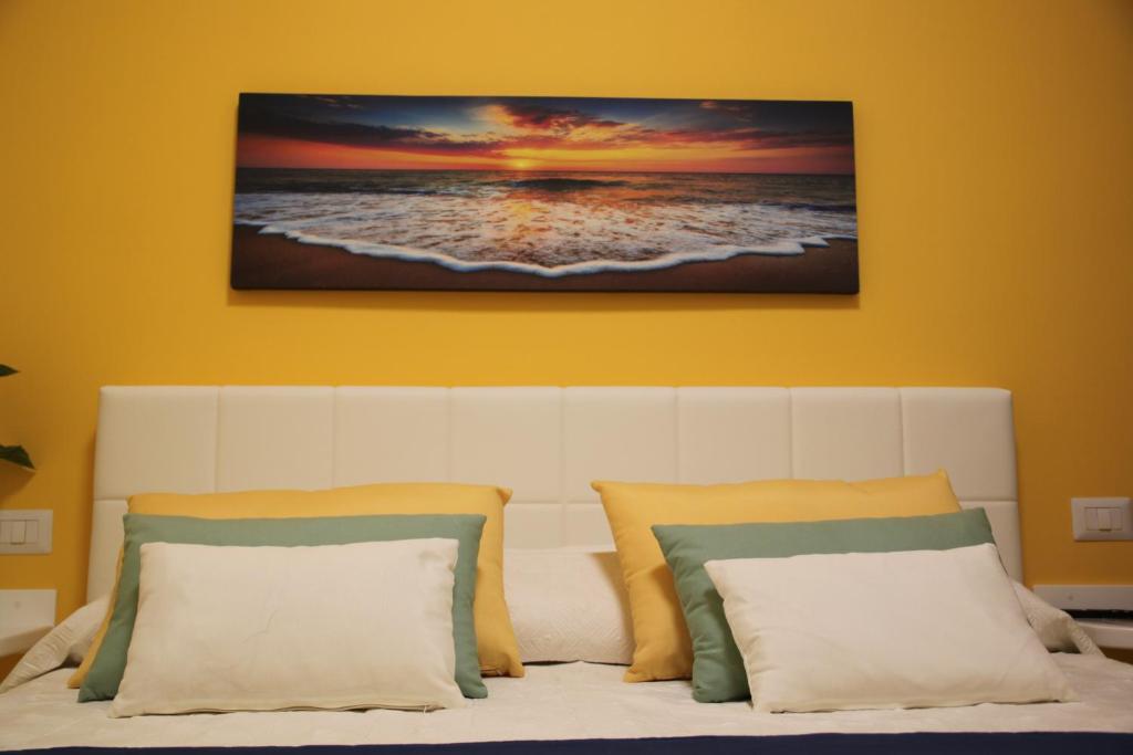a white bed with two pillows and a painting on the wall at BLU SEA SORRENTO in Sorrento