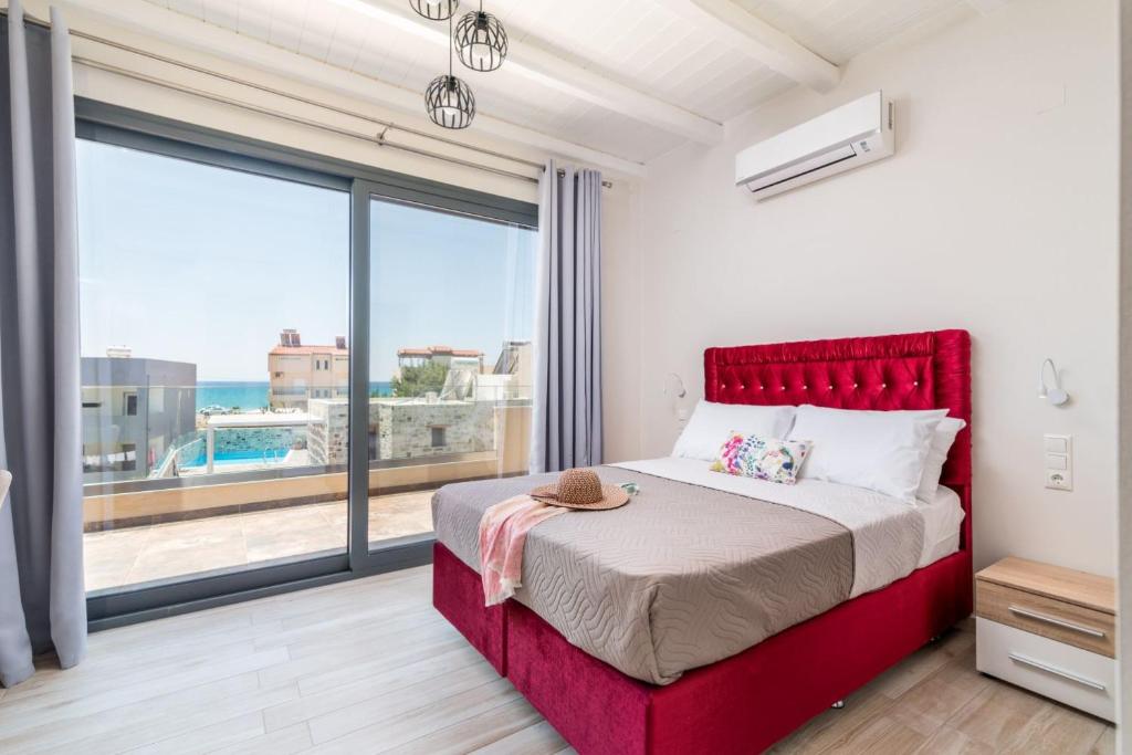 a bedroom with a red bed and a large window at EL.MA.RA. Luxury Villas in Kókkinos Pírgos
