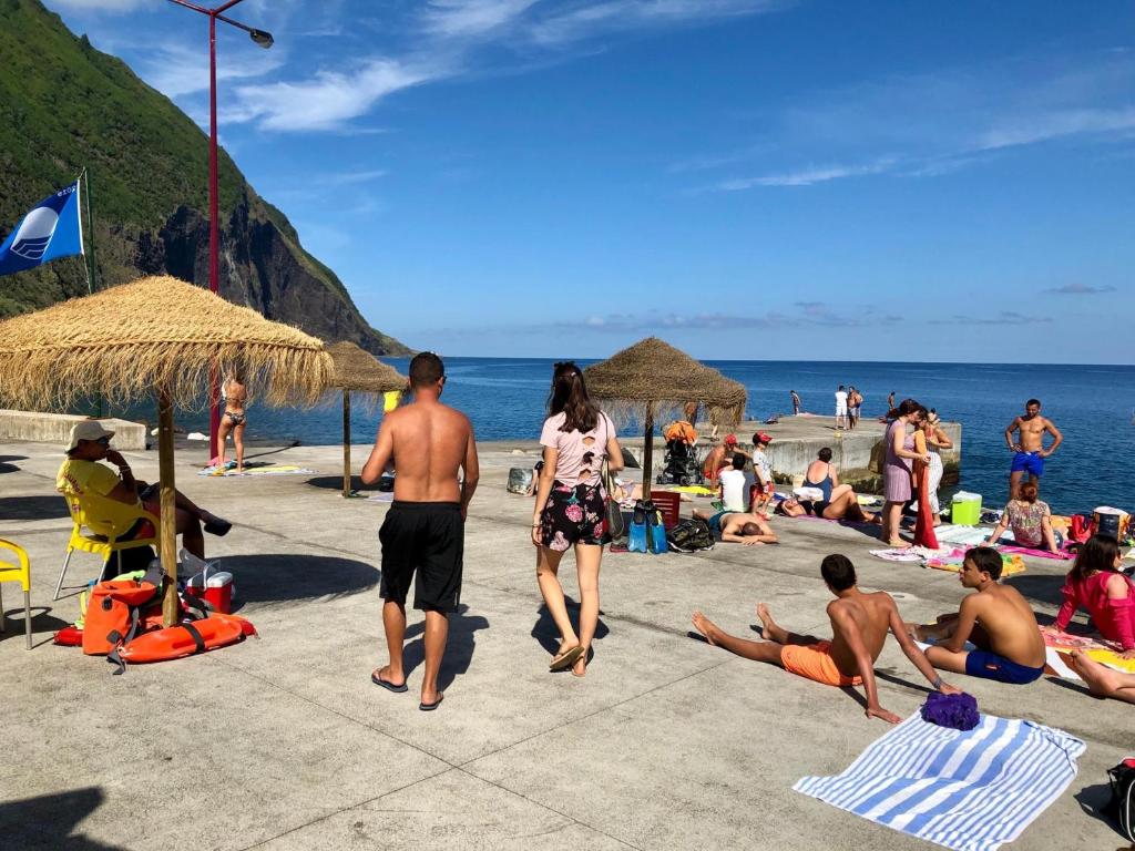 a group of people on a beach with umbrellas at Casa Auri in Faial da Terra