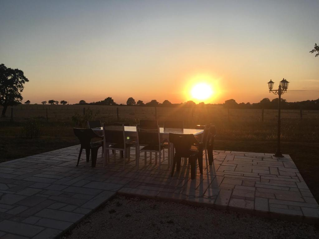 una mesa y sillas con la puesta de sol en el fondo en Gîte à l'orée de Grandchamp, en Grandchamp