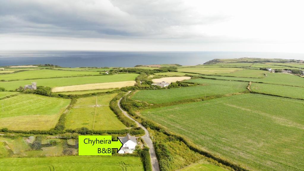 an aerial view of a green field with the ocean at Chyheira in Ruan Minor