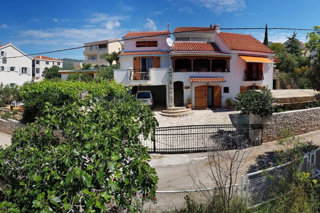 een wit huis met een hek ervoor bij Villa Apartments Oliva in Seget Vranjica