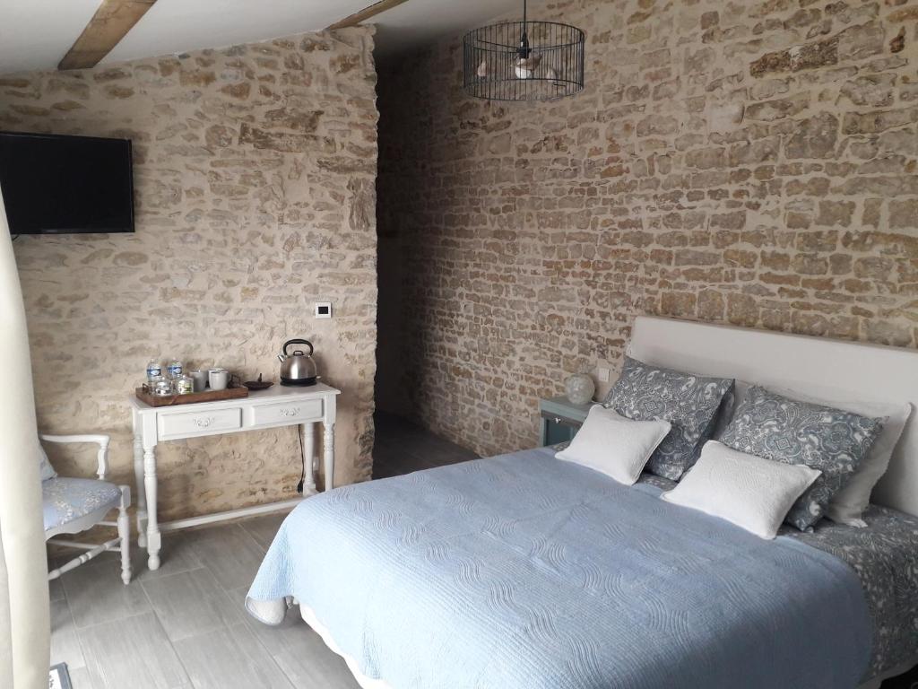1 dormitorio con cama y pared de ladrillo en l' Oiseau Bleu, en Bazoges-en-Pareds