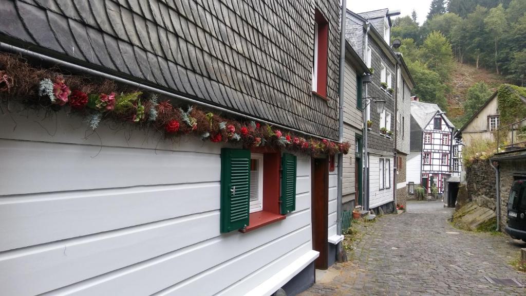 a building with red and green windows and flowers on it at HIER & JETZT in Monschau City in Monschau