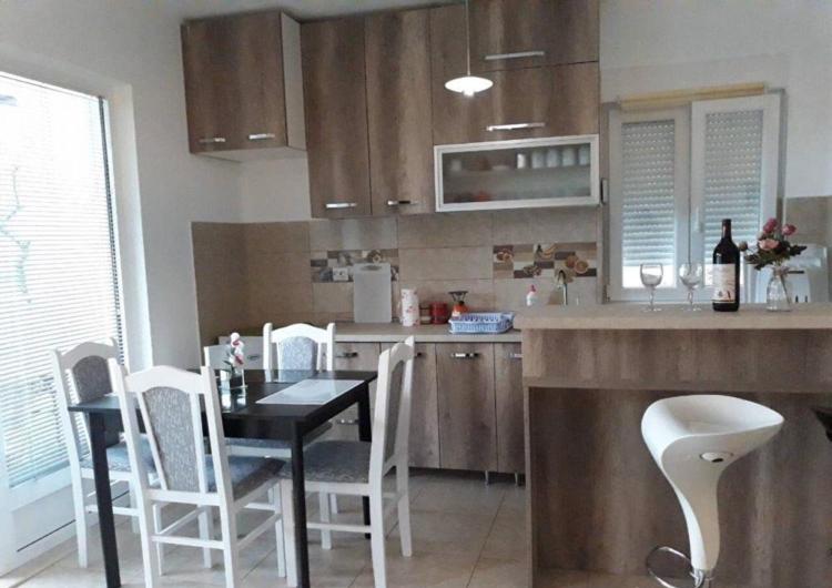 a kitchen with a table and white chairs and a counter at Apartment Iva in Bijela