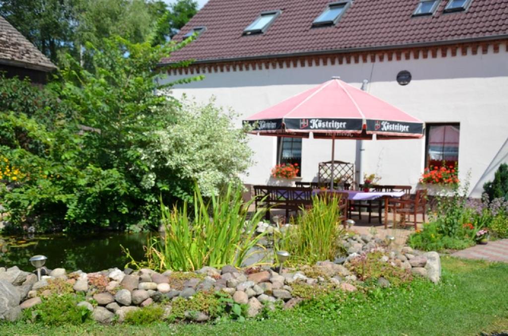 a patio with a table and umbrella in a garden at Storchennest an der Spree in Radinkendorf in Beeskow