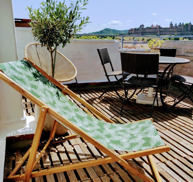 une chaise sur un balcon avec une table et des chaises dans l'établissement Appartement L'Oliveraie - La Cité plein les yeux, à Carcassonne