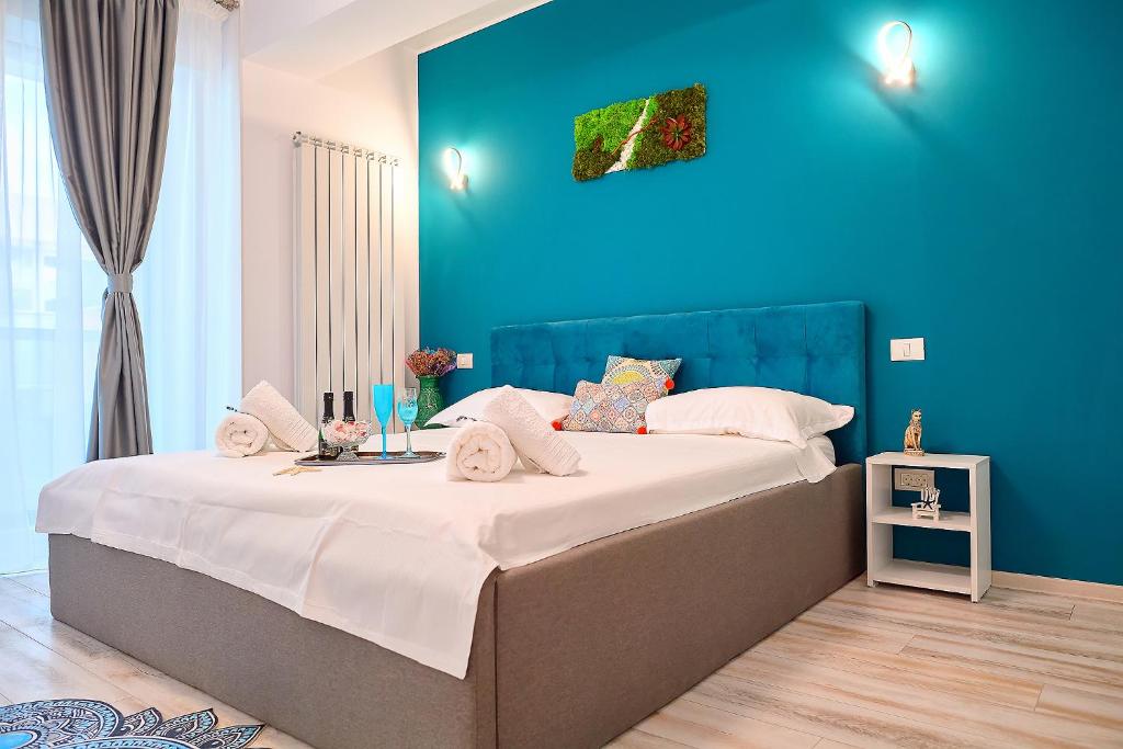 1 dormitorio con 1 cama grande y pared azul en Gota Place, en Mamaia