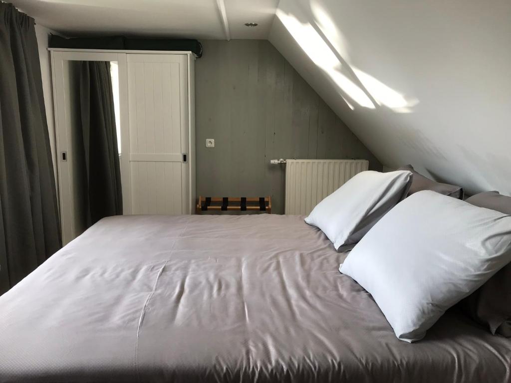 a bed with white sheets and pillows in a room at Studio Het Kommertjeshof in Burgh Haamstede