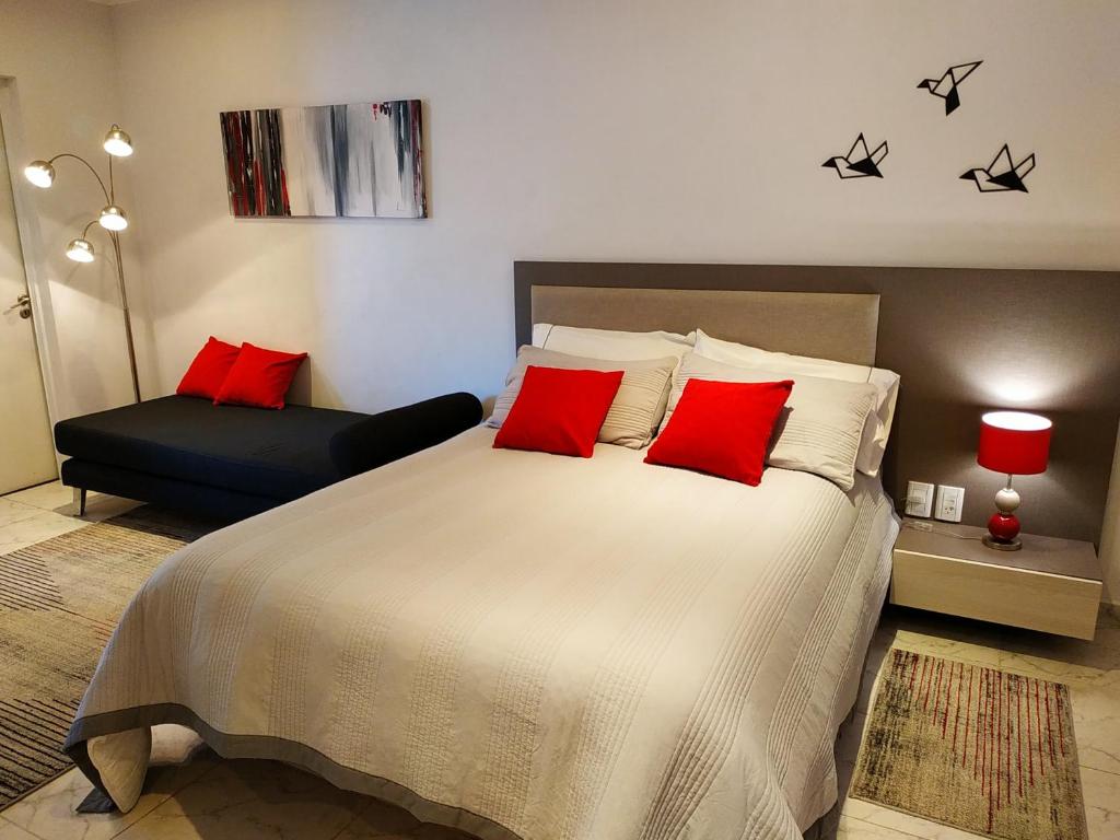 1 dormitorio con 1 cama grande con almohadas rojas en Complejo Cortazar Rafaela en Rafaela