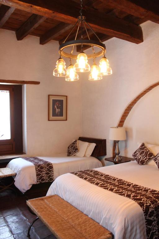 a bedroom with two beds and a chandelier at Mesón De Leyendas Breakfast & Downtown in Valle de Bravo