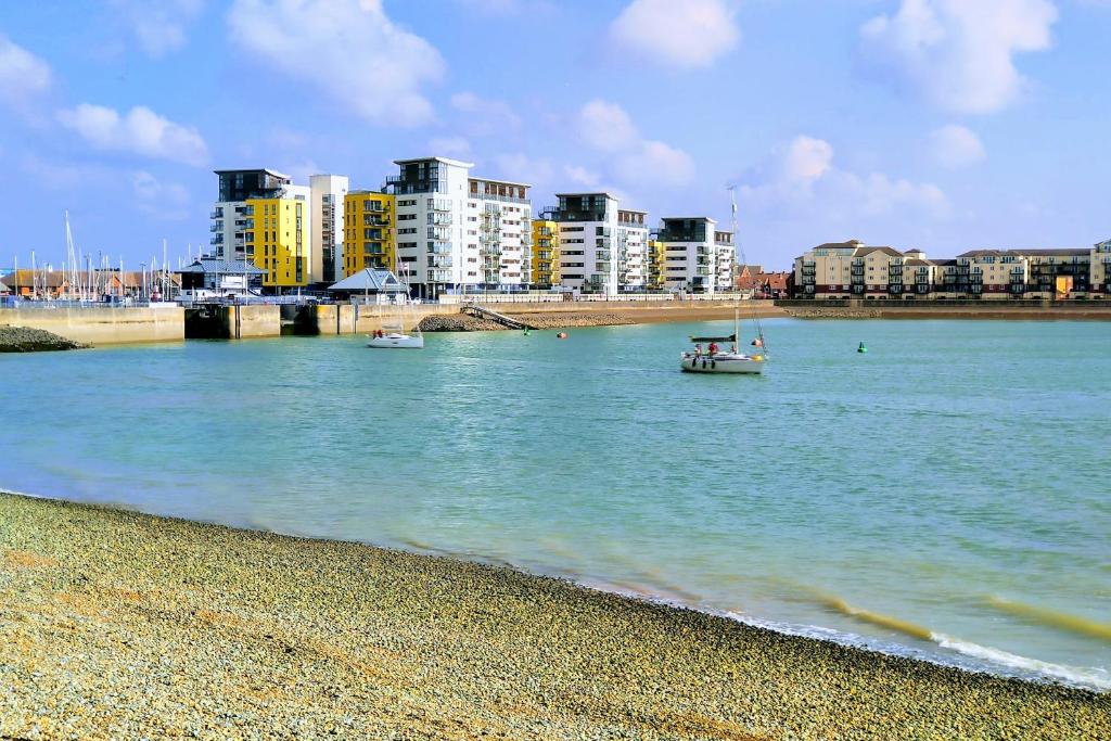 a boat in the water near a beach with buildings at Jacob's Place in Pevensey