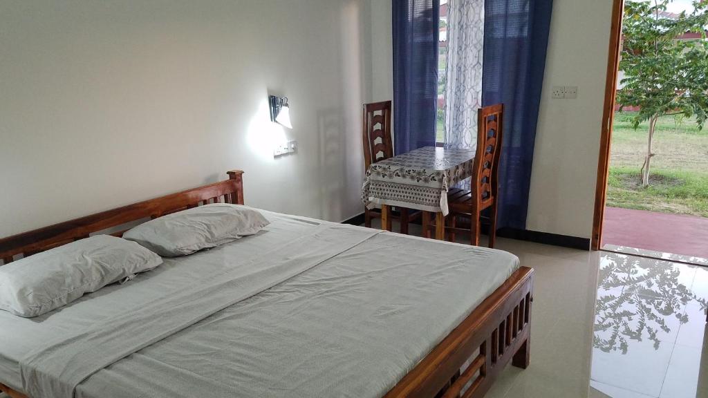 a bedroom with a bed and a table and a window at JEYs Place in Nilaveli
