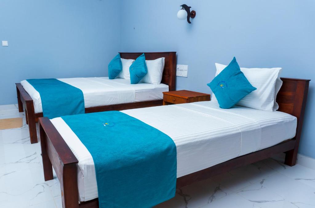 two beds in a room with blue walls at MRD Beach Hotel in Trincomalee