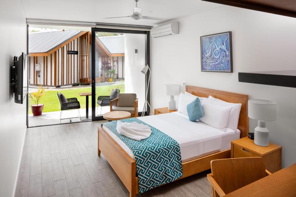 a bedroom with a bed and a balcony at Coral Sea Resort & Casino in Honiara