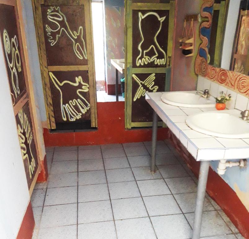 Baño con 2 lavabos y graffiti en las paredes en Mama Chelita en Nazca