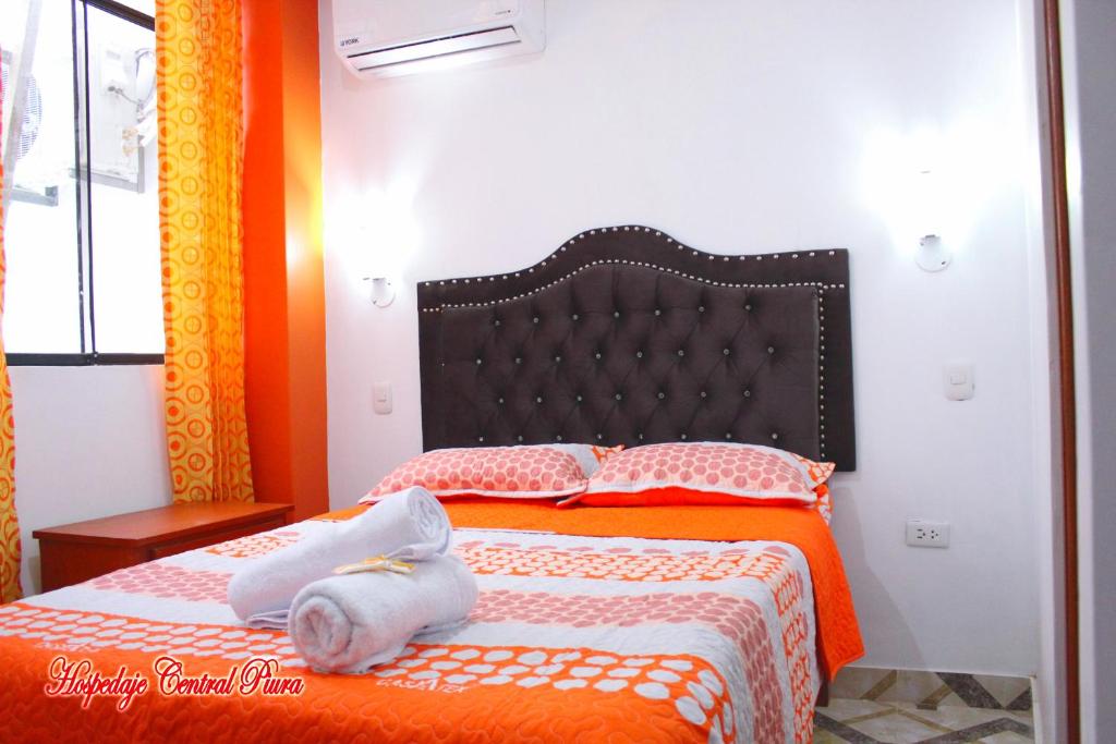 a bedroom with a bed with orange and white sheets at Hospedaje Central Piura in Piura