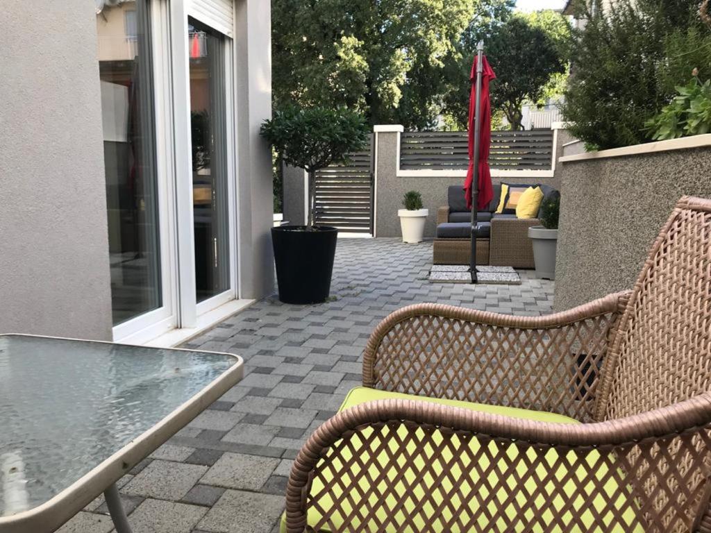 a patio with two wicker chairs and a glass table at Holiday Home Aspalathos in Split