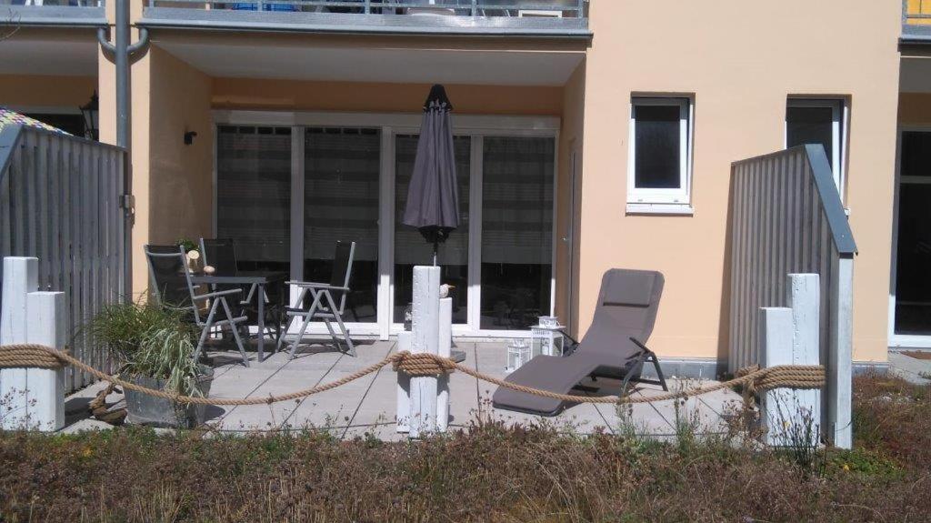 een paar stoelen en een parasol op een patio bij Ferienwohnung B4 Haus Elmsfeuer in Graal-Müritz