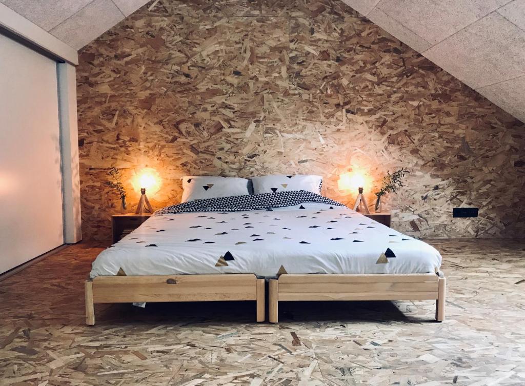 een slaapkamer met een groot bed en een stenen muur bij La Grande Maraudeuse in Theux